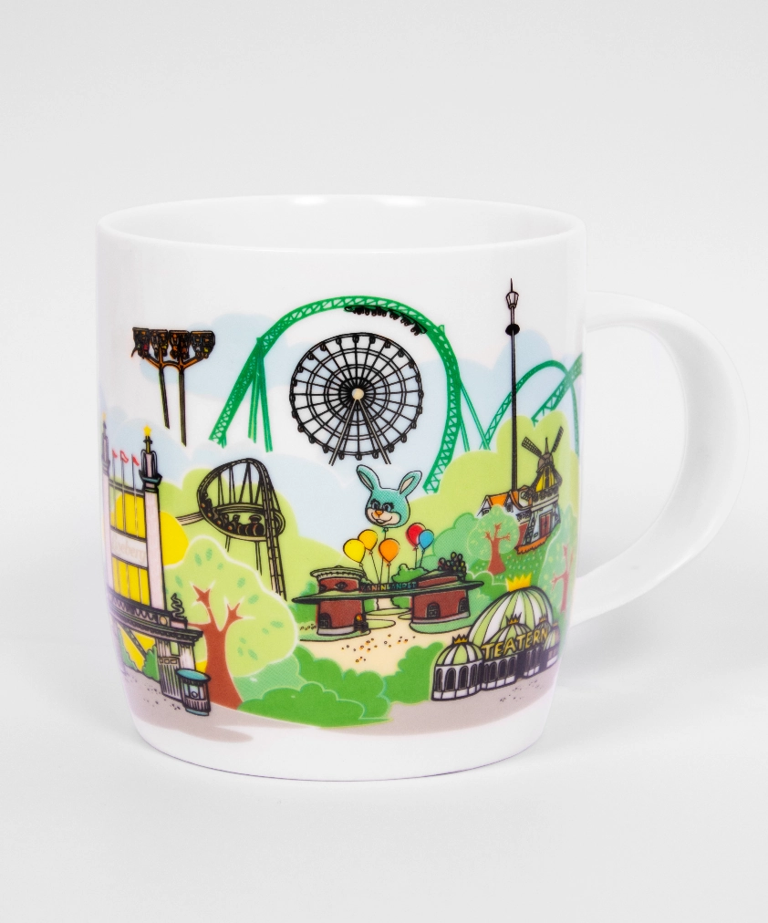 En vit mugg dekorerad med en färgstark tecknad illustration av nöjesparken Lisebergs skyline, som visar berg- och dalbanor, pariserhjulet och Lisebergskaninen.