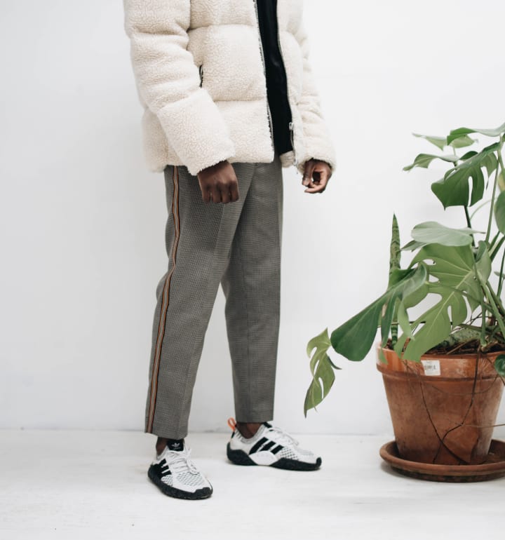 Ung man med en vit dunjacka och gråa byxor modellerar i en butik